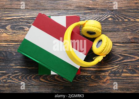 Moderne Kopfhörer und Bücher auf Holzhintergrund. Konzept des Studiums der italienischen Sprache Stockfoto