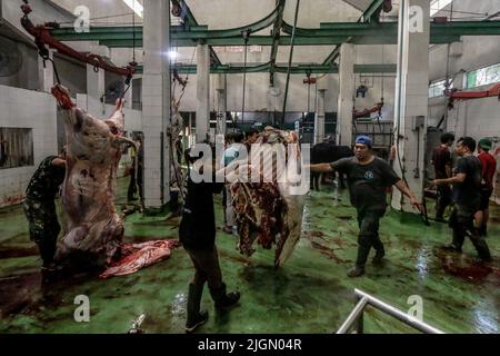 Ein Arbeiter trägt am 10. Juli 2022 im Schlachthof Bogor City in Bogor, West-Java, Indonesien, ein Stück Rindfleisch Stockfoto