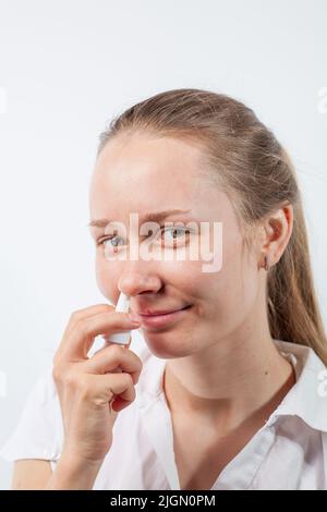 Das Mädchen tropft Nasentropfen aus einer laufenden Nase mit Influenza Stockfoto