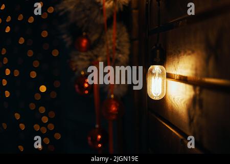 Weihnachtsschmuck und Glühlampe an der Holzwand. Stockfoto