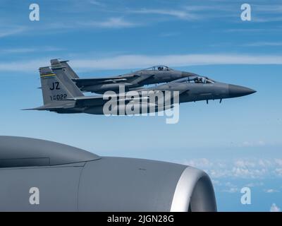 F-15 Adler fliegen mit dem 159. Fighter Wing, Louisiana, über den Flügel eines KC-135 Stratotankers mit dem 914. Air Betanking Wing Wing, New York, 10. Juli 2022 über den Südosten der Vereinigten Staaten. Die FW 159. trägt den Spitznamen „Bayou-Miliz“, die auf dem Schwanz der F-15 zu sehen ist. (USA Luftwaffe Foto von Tiffany A. Emery) Stockfoto