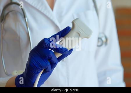 Arzt-Sonograf im medizinischen Gewand mit Ultraschallsonde Stockfoto