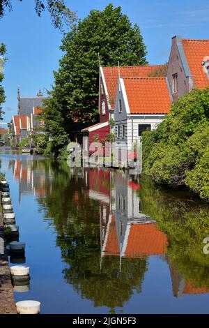 Bunte und historische Hausfassaden in De Rijp, Alkmaar, Nordholland, Niederlande, spiegeln sich auf einem Kanal Stockfoto