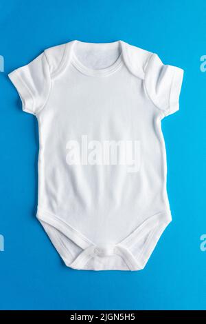 Flacher, weißer Bodysuit für kleine Kinder auf blauem Hintergrund für Jungen. Layout für die Gestaltung und Platzierung von Logos, Werbung. Nahaufnahme. Stockfoto