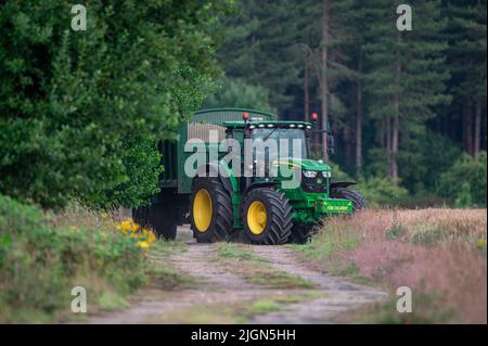 Ein John deere Traktor, der Getreide aus der Ernte auf einer Farm in North Norfolk, Großbritannien, karttiert Stockfoto