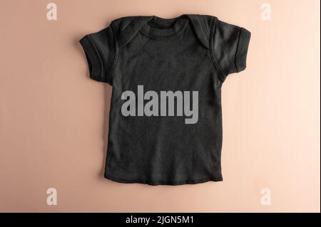 Flaches Modell eines schwarzen Kinder-T-Shirts auf einem rosa Hintergrund für Mädchen. Layout für die Gestaltung und Platzierung des Logos, Werbung. Stockfoto