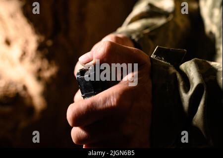 Das Magazin mit militärischen Kampfgewehren AK 74 füllen, einem Soldaten in einem Graben, der für ein Maschinengewehr Munitionsmaterial hält, der Krieg in der Ukraine. Stockfoto