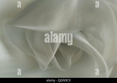 Grauer oder grüner Organza-Stoff. Zerknitterter oder gewellter Stoffhintergrund. Abstraktes Leinentuch mit sanften Wellen. Naturgarn. Geschmeidiges, elegantes Luxustuch Stockfoto