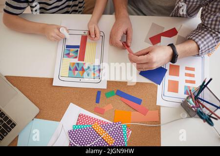 Oben Ansicht von Vater und Sohn sitzen am Tisch mit bunten Papierteilen und kleben Papier auf Tablettenmuster für Schulprojekt Stockfoto