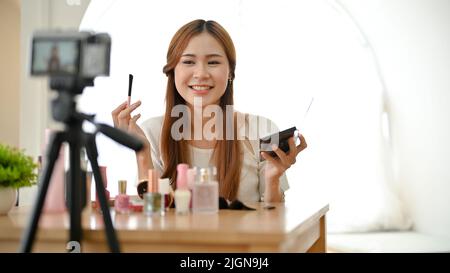Attraktive charmante Millennial asiatische weibliche Schönheit bloggerin Anwendung Kosmetik, Make-up und Aufnahme von Video. Stockfoto