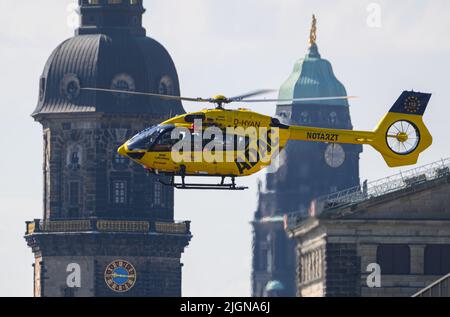 Dresden, Deutschland. 12.. Juli 2022. Der Rettungs- und Intensivhubschrauber Christoph vom ADAC Air Rescue Service landet vor der Altstadt mit dem Hausmannturm (l-r), dem Rathaus und der Semperoper. Heute findet im Internationalen Kongresszentrum (ICC) das "Symposium Sachsen" des ADAC Lufttrettung zu aktuellen Herausforderungen und Entwicklungen der schnellen Flughilfe statt. Kredit: Robert Michael/dpa/Alamy Live Nachrichten Stockfoto