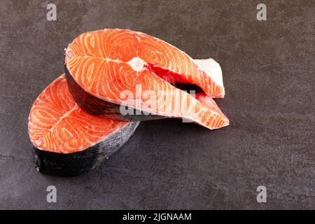 Zwei rohe Lachssteaks auf schwarzem Hintergrund Stockfoto