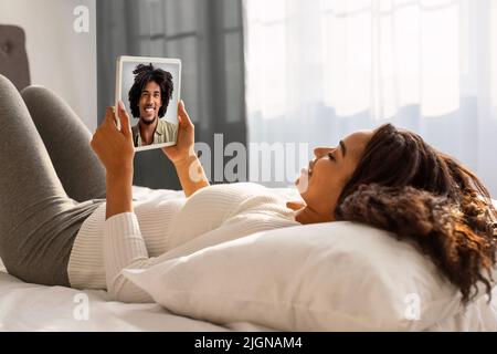 Junge schwarze Frau mit digitalen Tablet für virtuelle Chat mit Freund Stockfoto