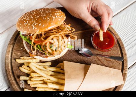 Mann tauche pommes in rote Sauce aus der Draufsicht Stockfoto