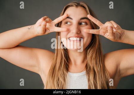 Nahaufnahme Spaß liebende Frau Frieden stiften Zeichen das Studio Stockfoto