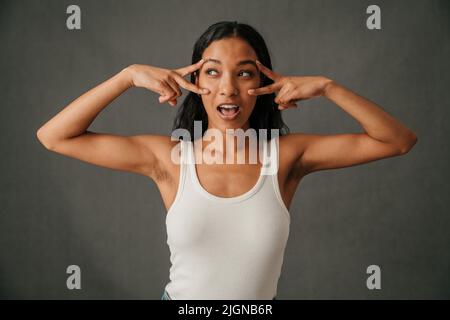 Afroamerikanische Frau, die ihre gut getönten Arme zeigt und Friedenszeichen macht Stockfoto