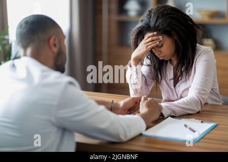 Männlicher Arzt mit Gespräch mit verärgert schwarze Frau Patient Stockfoto