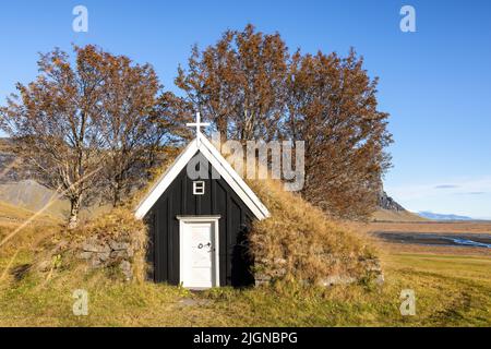 Alte schwarze Holzkirche im Süden Islands. Traditionelles Gebäude mit Rasenflächen und Dach, das in den kalten Wintern zur Isolierung beiträgt. Herbst Stockfoto