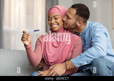 Eltern Werden. Porträt Von Schwarz-Muslimischen Ehegatten Mit Positivem Schwangerschaftstest Stockfoto