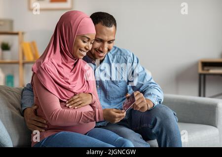 Zukünftige Eltern. Happy Black Muslim Paar Blick Auf Baby Sonographie Foto Stockfoto