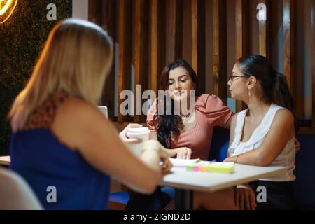 Studenten sitzen als Freunde beim Brainstorming im Café Stockfoto