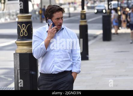 Johnny Mercer MP (Con: Plymouth Moor) - Minister für Veteranenangelegenheiten - auf seinem Mobiltelefon vor dem Kabinett in Whitehall, 11.. Juli 2022 Stockfoto