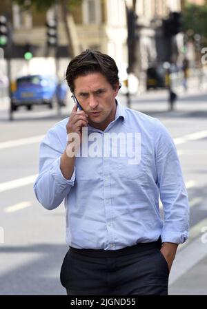 Johnny Mercer MP (Con: Plymouth Moor) - Minister für Veteranenangelegenheiten - auf seinem Mobiltelefon vor dem Kabinett in Whitehall, 11.. Juli 2022 Stockfoto