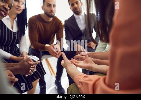 Verschiedene Menschen, die während der Gruppentherapie im Kreis sitzen, hören der Frau aufmerksam zu. Stockfoto