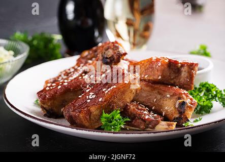Köstliche gegrillte Spare Rips auf dem Teller auf dunklem Hintergrund. Leckeres grillfleisch. Stockfoto