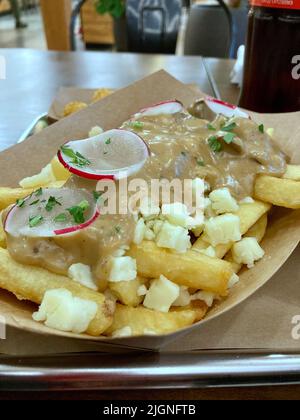 Köstliche Poutine, pommes Frites mit Soße oder Sauce garnieren mit Käse und rötlich Stockfoto