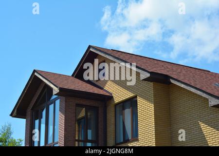 Backsteinhaus Dach mit Panoramafenster und Asphalt Schindle Dach. Dachfenster-Wand. Stockfoto