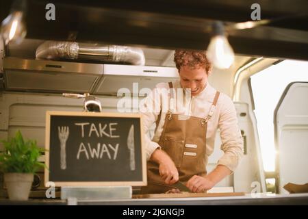Happy Cook Schneiden Zutaten in Food Truck Stockfoto