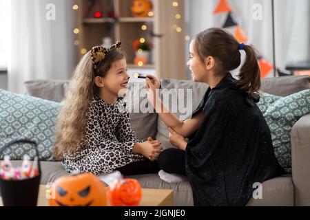 Mädchen, die zu Hause an halloween Gesichtsbemalung machen Stockfoto