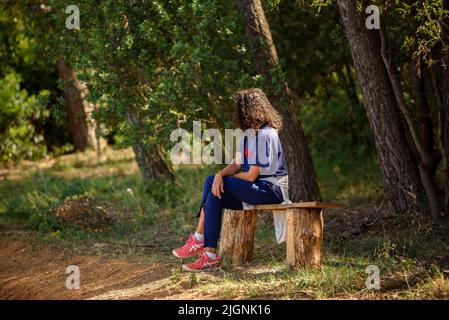 Ein Wanderer, der im Wald bei Sant Cugat del Vallès, im Naturpark Collserola (Barcelona, Katalonien, Spanien) sitzt, vor allem: Una senderista sentada Stockfoto