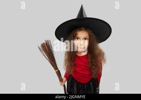 Mädchen in schwarzem Hexenhut mit Besen an halloween Stockfoto