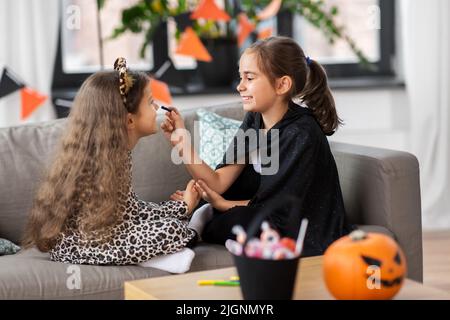 Mädchen, die zu Hause an halloween Gesichtsbemalung machen Stockfoto