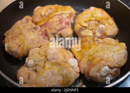 Gebratene Hähnchenschenkel auf einer schwarzen Antihaftpfanne. Frisch gebratenes Hähnchen mit Kurrfleisch, Tumeric und Koriander. Stockfoto