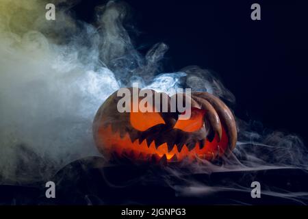 Komposition von halloween geschnitzten Kürbis mit Rauch auf schwarzem Hintergrund Stockfoto