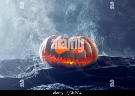 Komposition von halloween geschnitzten Kürbis mit Rauch auf schwarzem Hintergrund Stockfoto