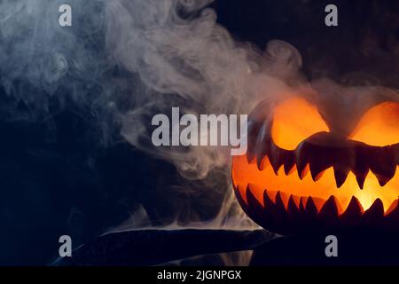 Komposition von halloween geschnitzten Kürbis mit Rauch auf schwarzem Hintergrund Stockfoto