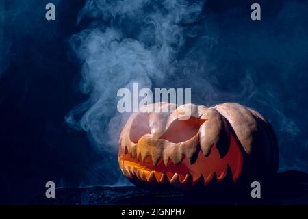 Komposition von halloween geschnitzten Kürbis mit Rauch auf schwarzem Hintergrund Stockfoto