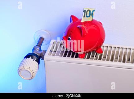 Sparen beim Heizen: Heizkörper und Thermostat mit Sparschwein und Geld Stockfoto