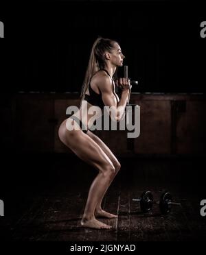 Weibliches Fitnessmodell mit getöntem Körper, das mit Gewichten trainiert, Großbritannien Stockfoto