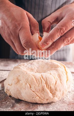 Das Ei knacken und in der Nähe des Teigs hinzufügen Stockfoto