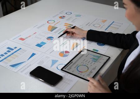 Die männlichen asiatischen Finanzmitarbeiter erklären die Performance der schnell wachsenden Balkengrafik des Unternehmens in diesem Jahr. Konzept des Finanzanalysten Stockfoto