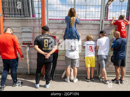 München, Deutschland. 12.. Juli 2022. Fans verfolgen das Training des FC Bayern auf dem Vereinsgelände hinter dem Sperrzaun. Kredit: Peter Kneffel/dpa/Alamy Live Nachrichten Stockfoto