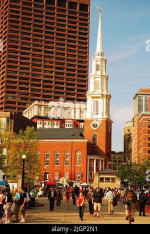 Pendler und Touristen gehen auf dem Bürgersteig vor dem Boston Common mit Blick auf die historische Park Street Church und das Finanzviertel in der Innenstadt Stockfoto