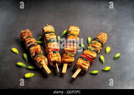 Hähnchen-Shish-Kebab mit Zucchini. Draufsicht.Gegrillte Hähnchenfleisch-Stücke auf Spieße.Gegrillter Hähnchenkebab mit Gemüse auf schwarzem Hintergrund. Stockfoto