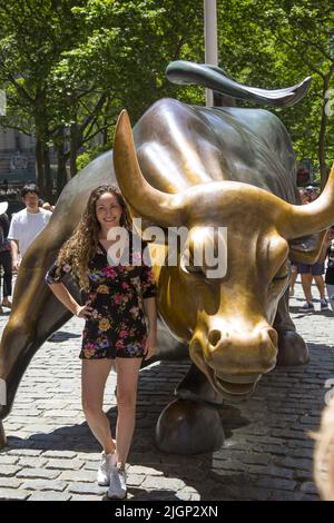 Touristen stehen an, um ihre Fotos mit dem berühmten Wall Street Bull am unteren Broadway in Manhattan, New York City, zu machen. Stockfoto
