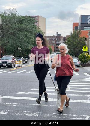 Jüngere und ältere Frau mit Hund joggen früh am Morgen zusammen. Brooklyn, NY. Stockfoto